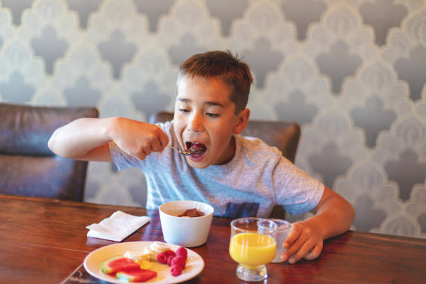 istock Mixed Ethnic Young Boy Eating Breakfast Cereal with Healthy Fruit and Milk 1147454751