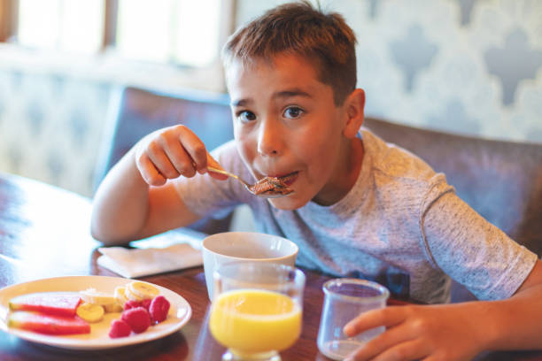 istock Mixed Ethnic Young Boy Eating Breakfast Cereal with Healthy Fruit and Milk 1147454778