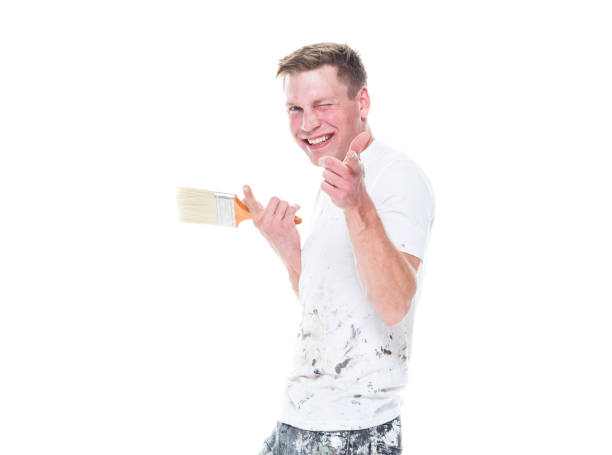 istock Handsome young male painter wearing staned clothes  on white background - finger gun 1147455072