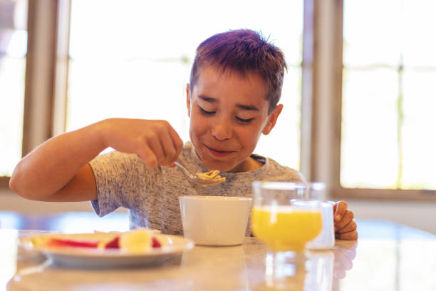 istock Mixed Ethnic Young Boy Eating Breakfast Cereal with Healthy Fruit and Milk 1147455327