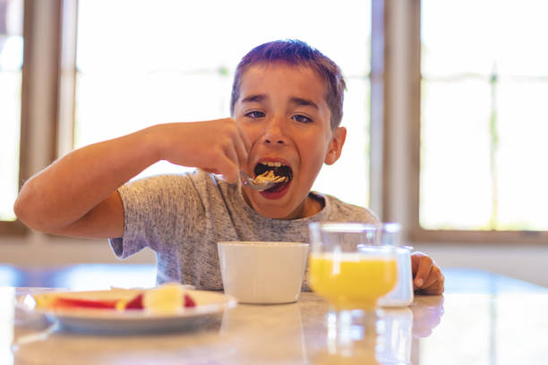 istock Mixed Ethnic Young Boy Eating Breakfast Cereal with Healthy Fruit and Milk 1147455379