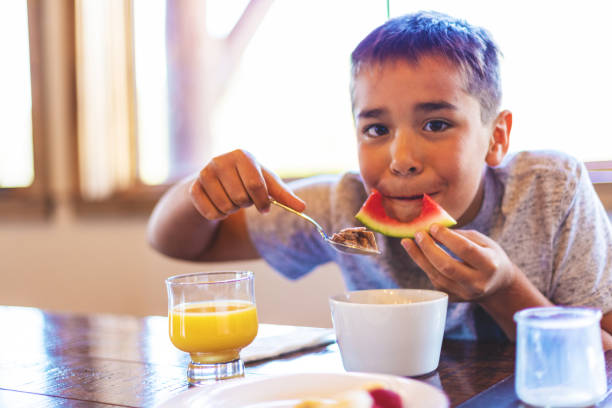 Mixed Ethnic Young Boy Eating Breakfast Cereal with Healthy Fruit and Milk