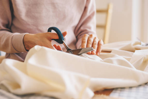 Woman cutting fabric with pinking shears Close up of woman's hand cutting fabric with pinking scissors Stitch stock pictures, royalty-free photos & images