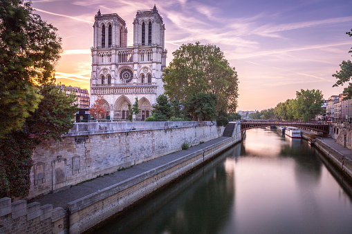 Notre Dame cathedral with houseboats on Seine during spring time in Paris, France