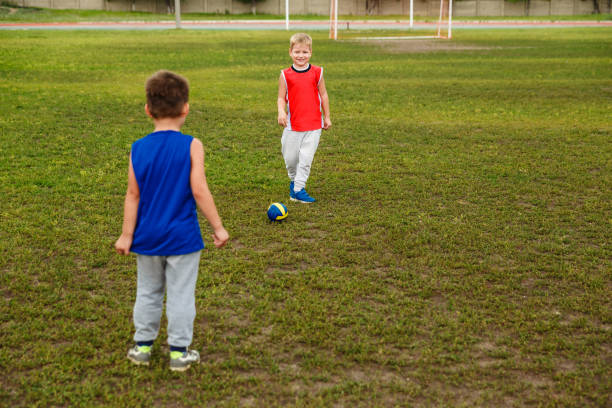istock two boys in uniform playing football on the green grass 1147465869