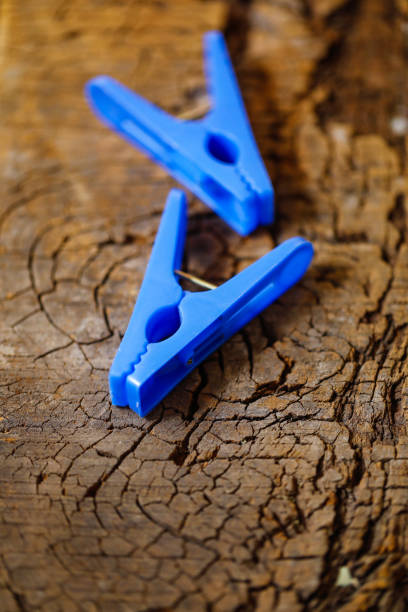 Rusty rustic run down weathered distressed clothespin or metallic clips hanging against messy dirty white wall background with selective focus on middle clip leaving copy space
