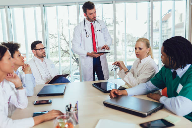 istock Medical team sitting and discussing at the table in the office, using digital tablet. 1147467103