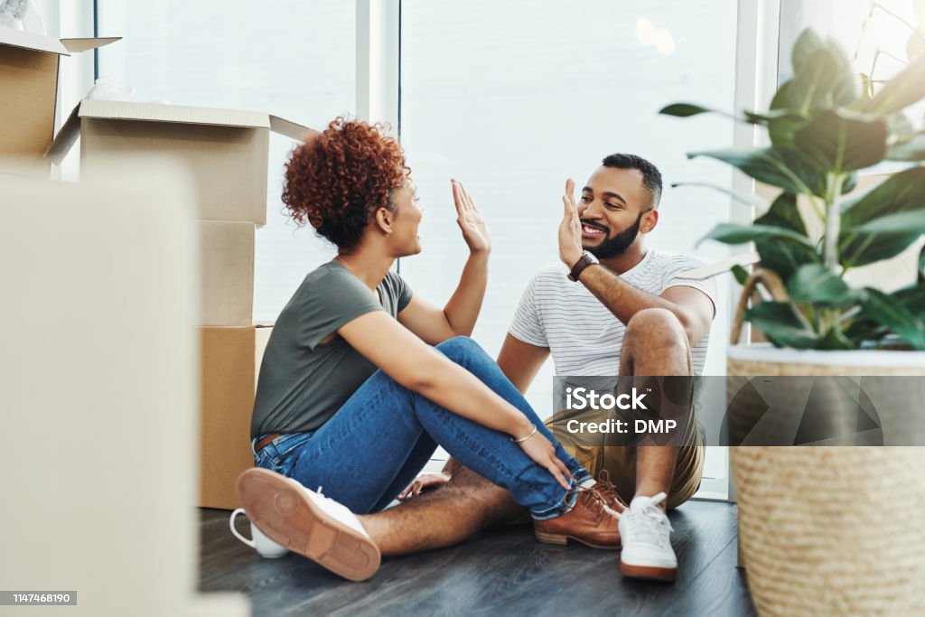 Well done on securing a new castle for us! Shot of a young couple giving each other a high five while moving house Moving House Stock Photo