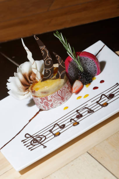 Vanilla dessert with chocolate, plum, strawberries and pitaya accompanied by musical notes drawn with melted chocolate.