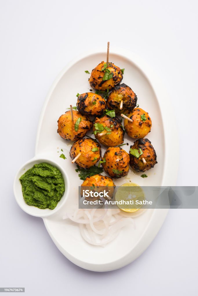 Tandoori aloo are roasted potatoes with Indian spices. It's a party appetiser served with green chutney. selective focus Appetizer Stock Photo
