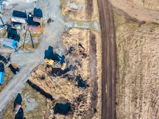 掘削機と黄色のトラクターの空中ビューは晴れた日に道路や建物の建設のために地球からの鉱物の抽出中に砕石、セメントや砂を輸送します。 - earth mover working field dirt ストックフォトと画像