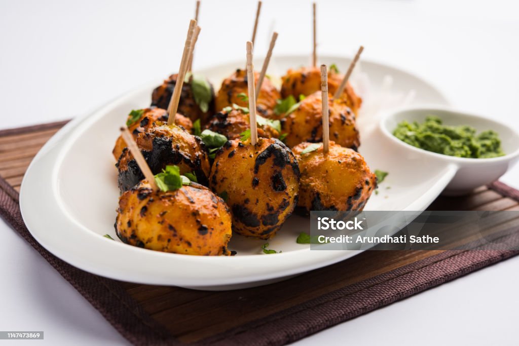 Tandoori aloo are roasted potatoes with Indian spices. It's a party appetiser served with green chutney. selective focus Appetizer Stock Photo