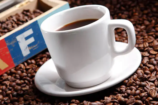 Photo of Coffee with grains and sweet bread. Coffee is a brewed drink prepared from roasted coffee beans, the seeds of berries from certain Coffea species.