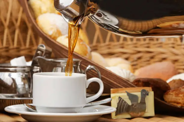 Photo of Coffee with grains and sweet bread. Coffee is a brewed drink prepared from roasted coffee beans, the seeds of berries from certain Coffea species.