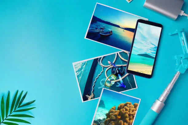 Smartphone with photos of the tropics on the screen, photos with landscapes and the sea from a vacation on a blue background. Flat lay.