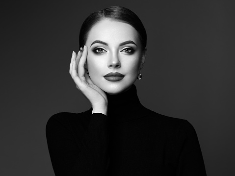 Beautiful Young Woman with Clean Fresh Skin. Perfect Makeup. Beauty Fashion. Plump Lips. Cosmetic Eyeshadow. Smooth Hair. Girl in Black Turtleneck. Black and white photo