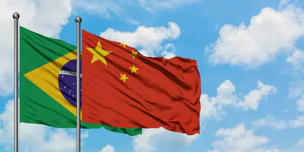 Brazil and China flag waving in the wind against white cloudy blue sky together. Diplomacy concept, international relations.
