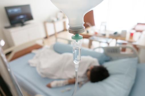 El niño se enferma de la gripe necesita ser admitido en el hospital con solución salina intravenosa (IV) presión de la mano en línea photo