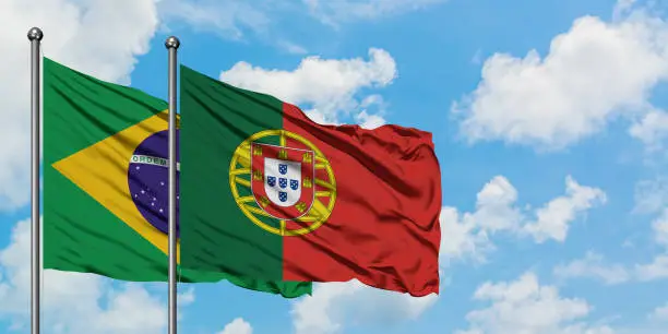 Brazil and Portugal flag waving in the wind against white cloudy blue sky together. Diplomacy concept, international relations.