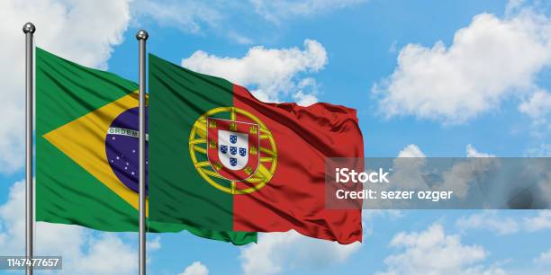 Foto de Bandeira De Brasil E De Portugal Que Acena No Vento De Encontro Ao Céu Azul Nebuloso Branco Junto Conceito Da Diplomacia Relações Internacionais e mais fotos de stock de Portugal