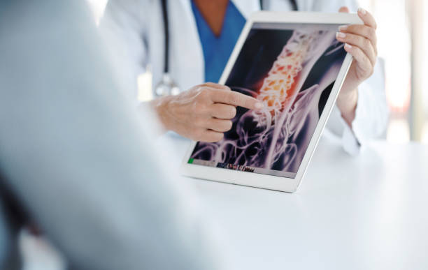 Imaging evaluation is crucial in confirming a diagnosis Shot of a doctor showing her patient his scan on a digital tablet spinous process stock pictures, royalty-free photos & images