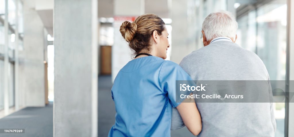 Making sure he gets his daily exercise Shot of a female nurse assisting her senior patient while walking Nursing Home Stock Photo
