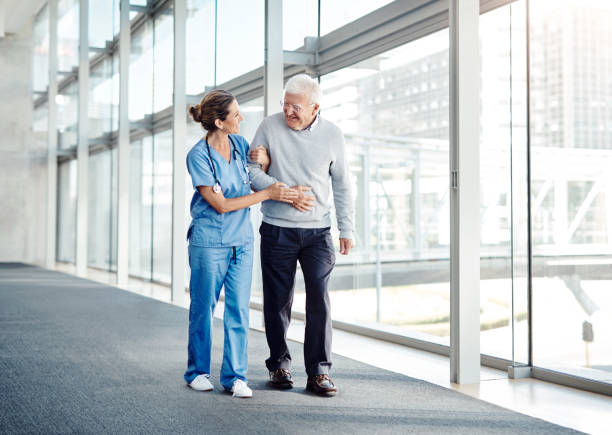 You sure know how to make this walk enjoyable Shot of a female nurse assisting her senior patient while walking locking-arms stock pictures, royalty-free photos & images