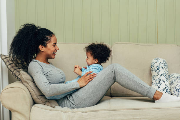 istock Smiling mother lying on couch with her baby on hips 1147479413