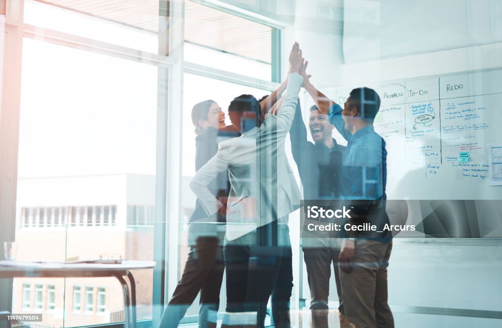 Business is winning when we stick together Shot of a group of young businesspeople joining hands in solidarity in a modern office Business Stock Photo