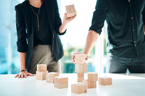 Cropped shot of a businessman and businesswoman having a meeting with building blocks in a modern office