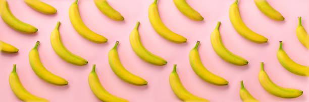 Geometric colorful fruit pattern. Bananas over pink background. Banner. Top view. Pop art design, creative summer concept. Minimal flat lay style.