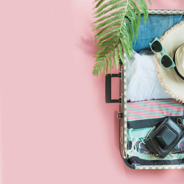 istock Open suitcase with female clothes for trip on pastel pink. Top view with copy space. Summer concept. 1147479842