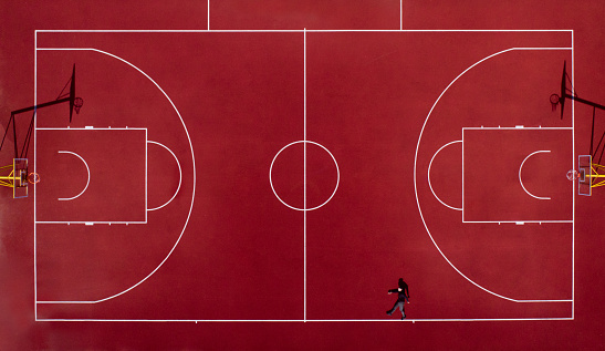 Drone shot of the basketball court and a man who is pretending to walk on the line.