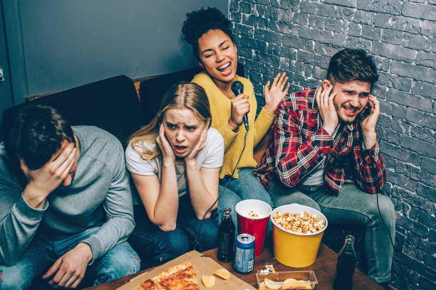 A funny picture of afro-american girl singing a song very loud. Unfortunately she doesn't have a good voice so that's why her friends have closed their ears and suffering from a noise. stock photo
