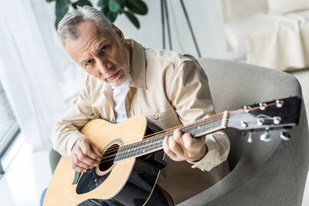 istock senior man playing acoustic guitar and looking at camera 1147492482