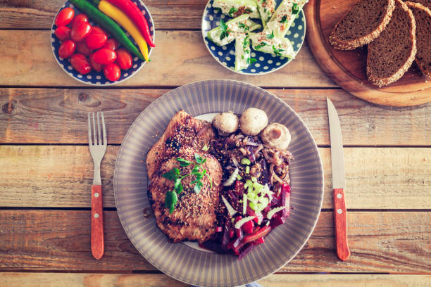 Top view food dish with roast beef, green fresh asparagus and rice garnished with tomatoes and lettuce.