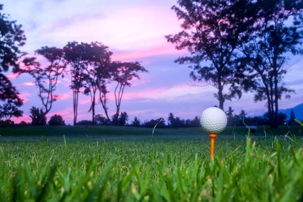 golf ball on tee at 1st hole tee off with blur green grass foreground and blur colorful sky with silhouette trees background during sunrise, thailand - golf ball spring cloud sun imagens e fotografias de stock