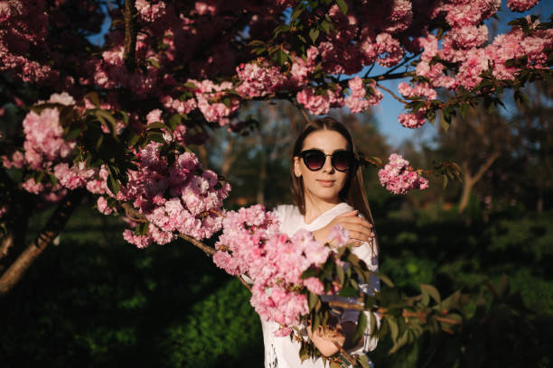 istock Beautiful woman in sunglasses stand in sakura tree 1147498558