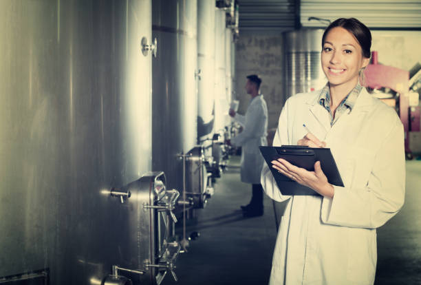 istock Female winery employee in uniform taking off data 1147498743