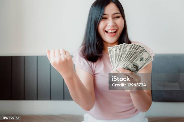 Closeup Portrait Of Attractive Woman Holding Money Cash From Savings With Happy Expression On Her Bedroom Business Financial And Savings Concept Stock Photo - Download Image Now