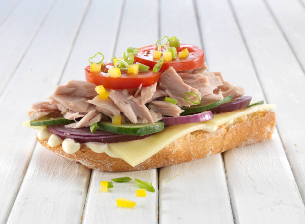 Sandwiches with tomatoes, basil and tuna fish on wooden cutting board on white background. Healthy breakfast, tapas, snack -