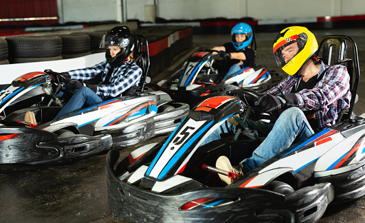 active man and women competing on racing cars at kart circuit