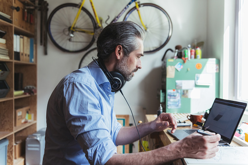 Designer with headphones working at wooden desk in home office