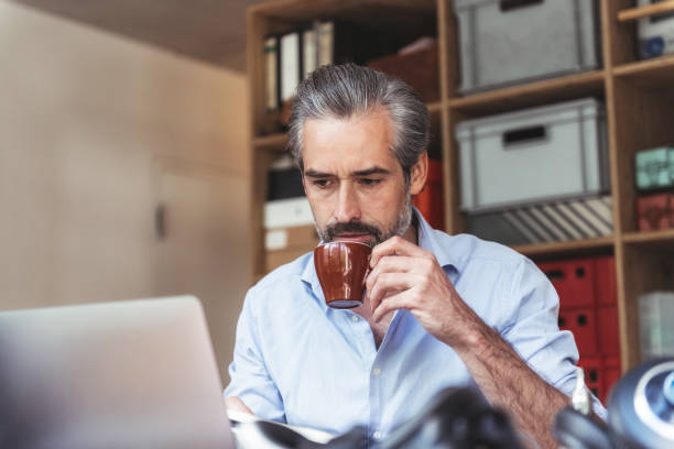 istock handsome bearded businessman having coffee at work desk 1147501366