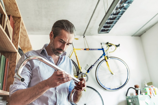 handsome bearded men holding bicycle handlebar in workshop