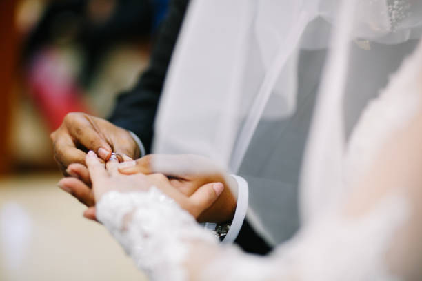 istock Bridegroom putting on the wedding ring for the bride 1147506566