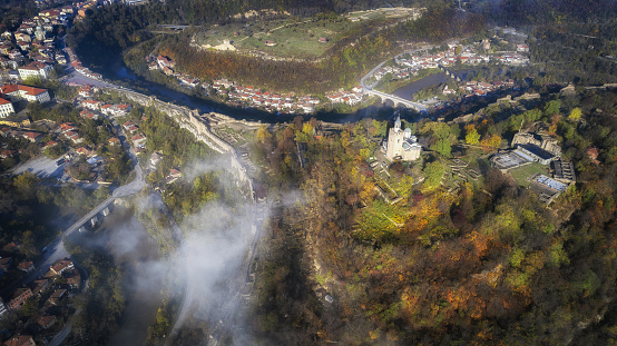Drone's flight over a historical place, old town of Veliko Turnovo with autumn fog, ancient fortress over the river Yantra, middle ages site, historical famous place in Europe, urban cityscape background