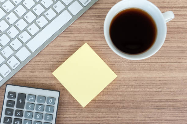 istock Computer keyboard, coffee, calculator and sticky note on top of wooden table 1147507823