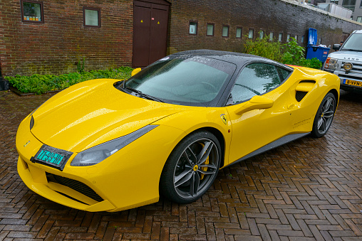 Yellow Ferrari 488 GTB sports car parked on the street in the rain in Zwolle, The Netherlands. The Ferrari 488 GTB (Tipo F142M) is a mid-engined sports car powered by a 3.9-litre twin-turbocharged V8.