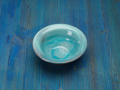 Empty Turquoise bowl cup on blue wooden table